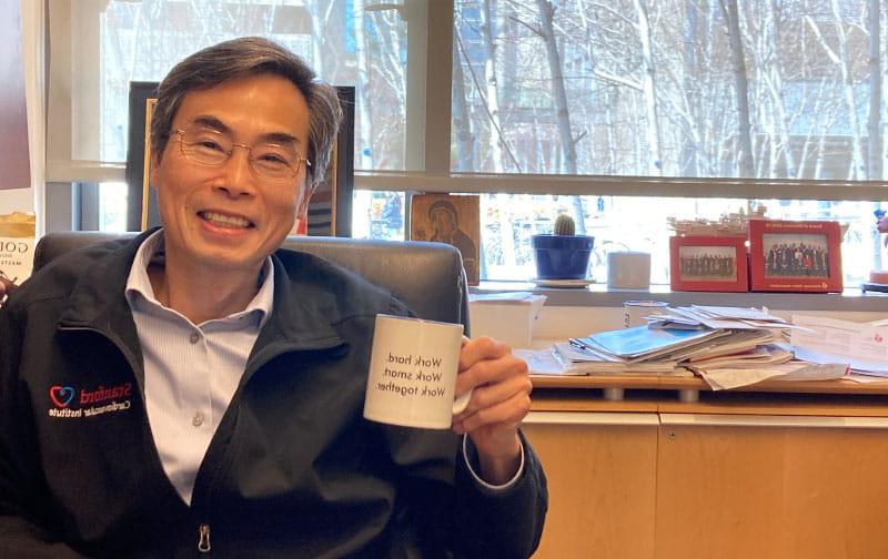 In his office, Dr. 约瑟夫·吴(Joseph Wu)的咖啡杯上印着他教给徒弟们的箴言:“努力工作/聪明工作/共同努力。.“那个杯子是其中一个学员送的礼物. (American Heart Association)