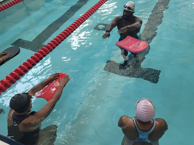 Brandon King (top), 塔妮卡·史密斯(右)和卡梅利亚·琼斯(左)在夏洛特西夏洛特高中的游泳池上游泳课, North Carolina. 金几年前学会了游泳，现在是一名教练. (Photo courtesy of Nadine Ford)